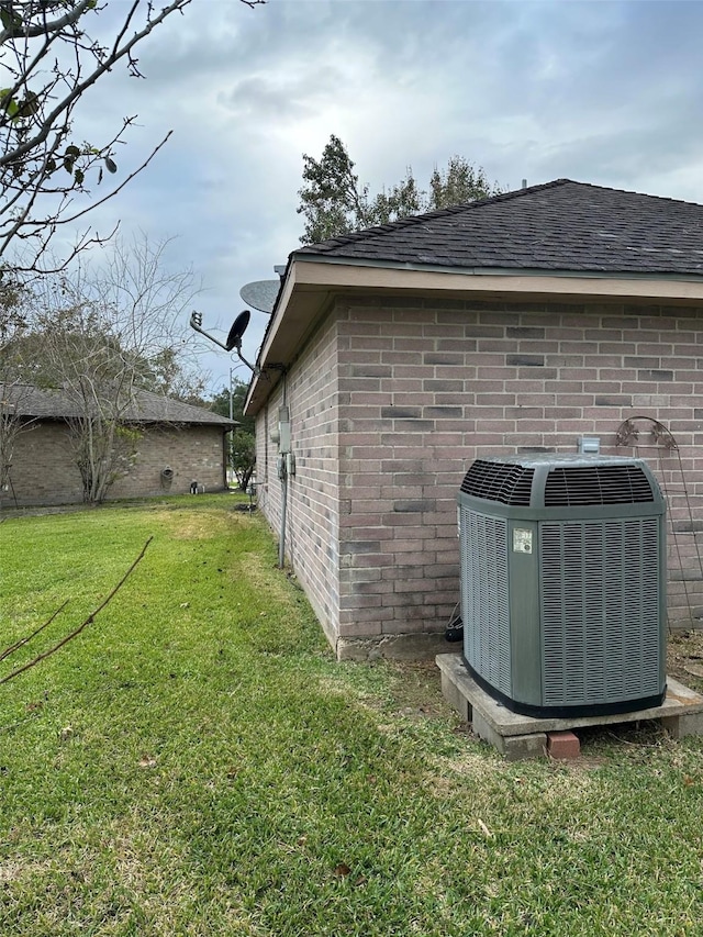 view of side of property with a yard and central air condition unit