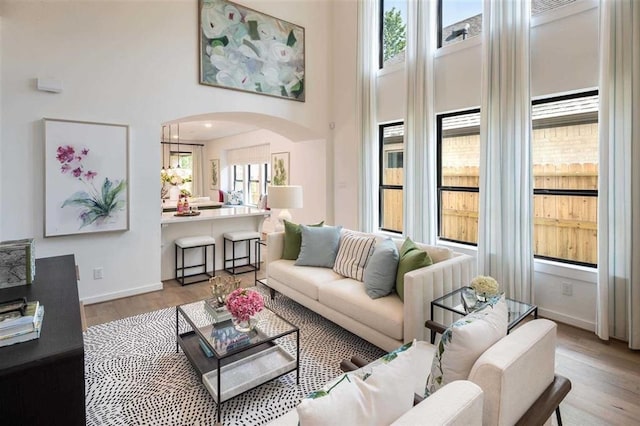 living room with a high ceiling, light wood-type flooring, and plenty of natural light