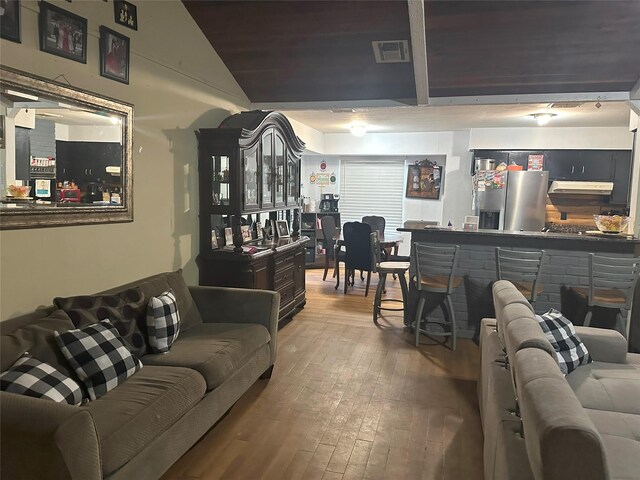 living room with lofted ceiling, hardwood / wood-style floors, and indoor bar