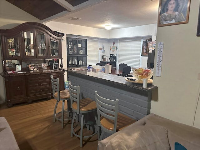 bar featuring dark brown cabinets and light hardwood / wood-style flooring