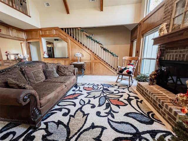 living room with beamed ceiling, a high ceiling, a wealth of natural light, and a fireplace