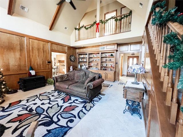 tiled living room featuring beamed ceiling, high vaulted ceiling, ceiling fan, and wooden walls