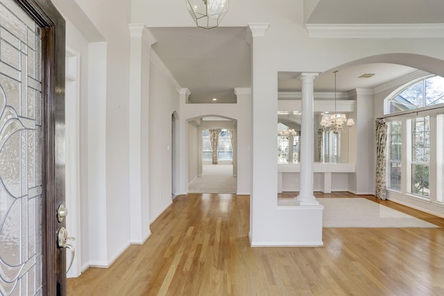 foyer with ornate columns, crown molding, light hardwood / wood-style flooring, and a notable chandelier