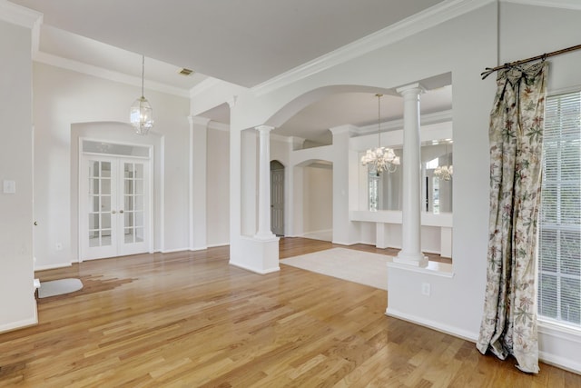 interior space with french doors, decorative columns, crown molding, a notable chandelier, and hardwood / wood-style floors