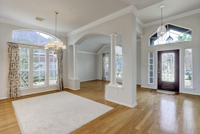 entryway with ornate columns, ornamental molding, wood-type flooring, an inviting chandelier, and lofted ceiling