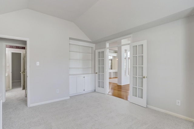 unfurnished bedroom with light carpet, french doors, and lofted ceiling