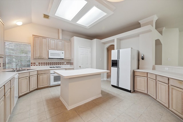 kitchen with sink, light tile patterned floors, white appliances, and light brown cabinets