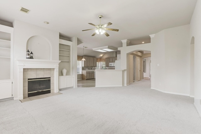 unfurnished living room featuring a tile fireplace, ceiling fan, and light colored carpet