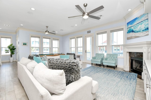 living room with a premium fireplace, light hardwood / wood-style flooring, crown molding, and french doors