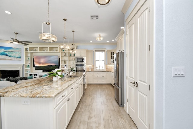 kitchen featuring light stone countertops, a large island, stainless steel appliances, light hardwood / wood-style flooring, and decorative light fixtures