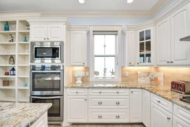 kitchen with tasteful backsplash, white cabinets, and stainless steel appliances