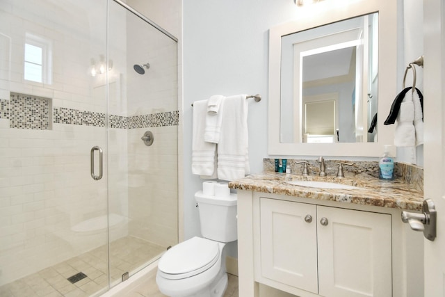 bathroom featuring vanity, toilet, and a shower with shower door