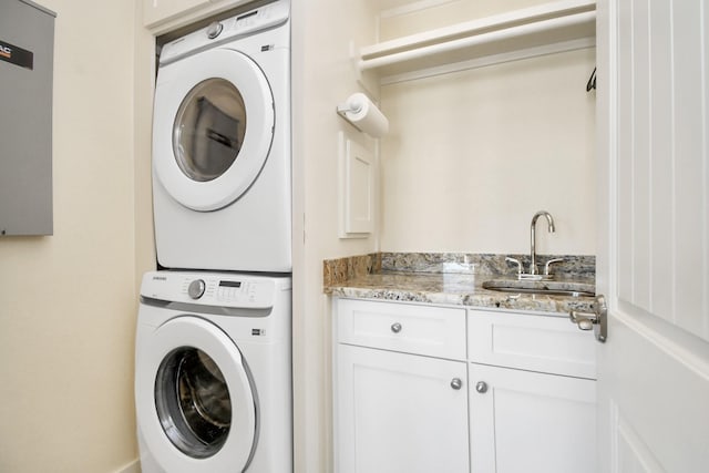 washroom featuring cabinets, stacked washer / drying machine, and sink