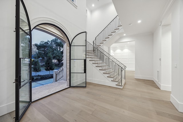 entrance foyer featuring crown molding, light hardwood / wood-style flooring, and french doors