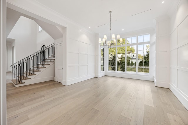 unfurnished dining area featuring an inviting chandelier and light hardwood / wood-style flooring