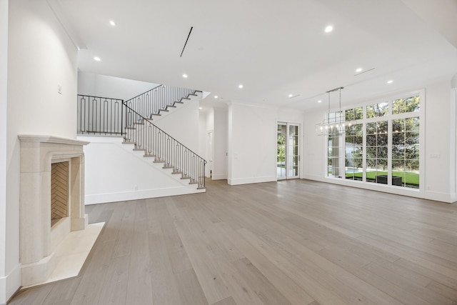 unfurnished living room with a fireplace, light hardwood / wood-style flooring, and an inviting chandelier