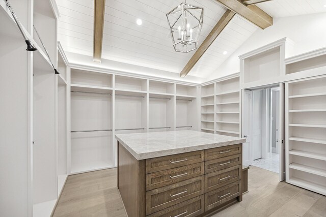 spacious closet featuring a notable chandelier, vaulted ceiling with beams, and light hardwood / wood-style flooring