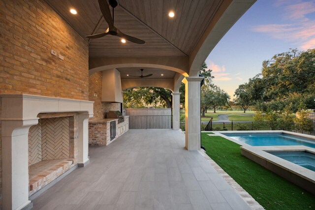 patio terrace at dusk featuring ceiling fan, area for grilling, a swimming pool with hot tub, and a grill