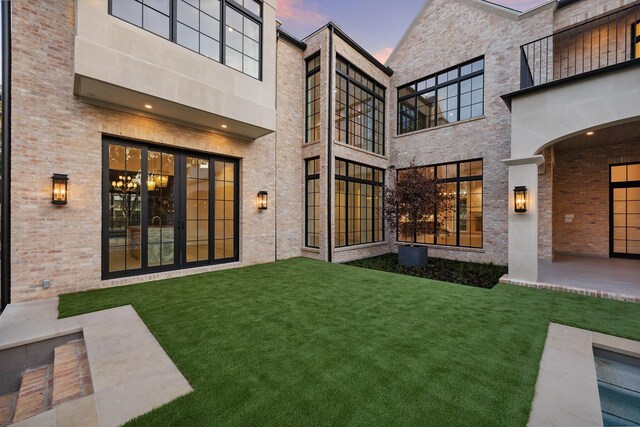 back house at dusk with a lawn