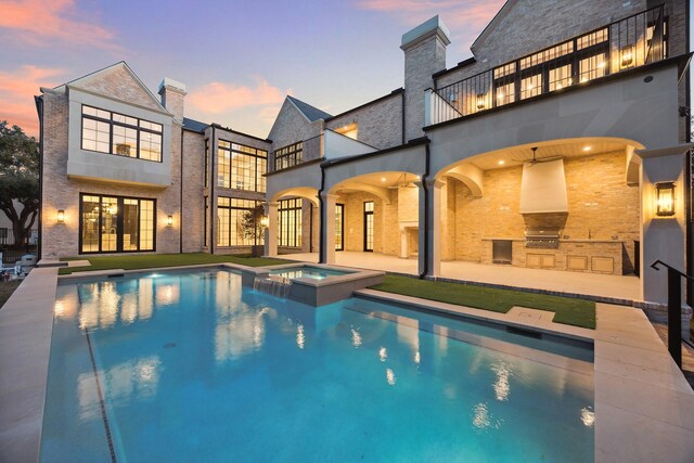 pool at dusk featuring area for grilling, a patio area, exterior kitchen, and an in ground hot tub