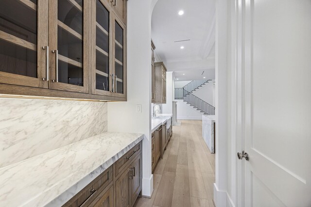 bar featuring light stone counters, sink, and light hardwood / wood-style flooring