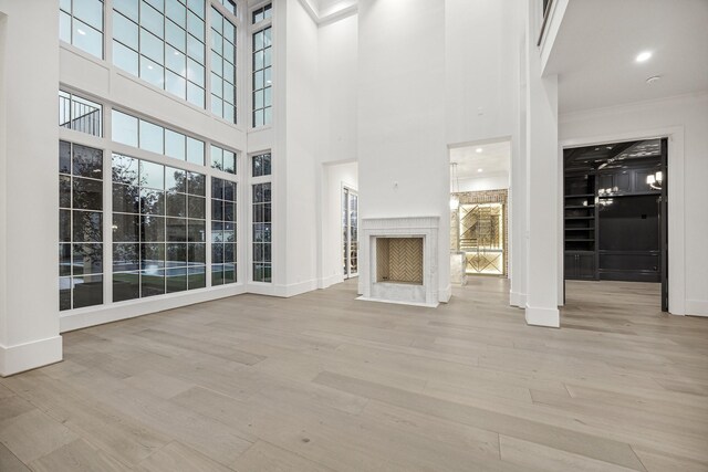 unfurnished living room with a fireplace, a high ceiling, and light wood-type flooring