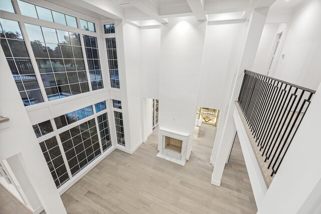 interior space with beam ceiling, hardwood / wood-style floors, and a towering ceiling