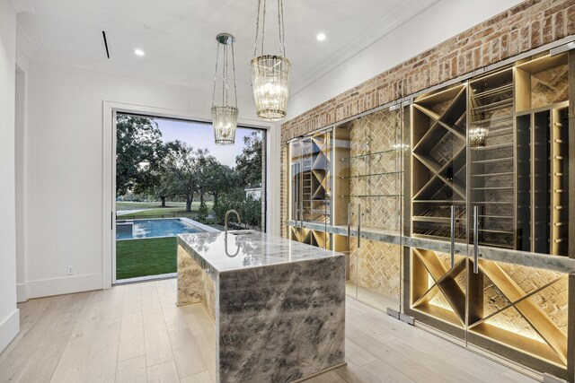 wine room featuring crown molding, light hardwood / wood-style flooring, and an inviting chandelier