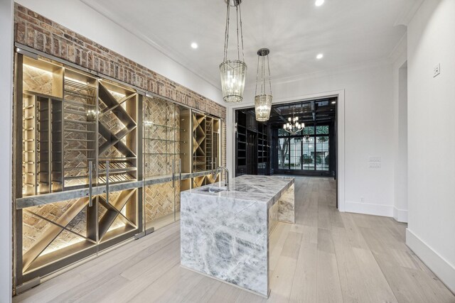 wine cellar with crown molding, a chandelier, and light wood-type flooring