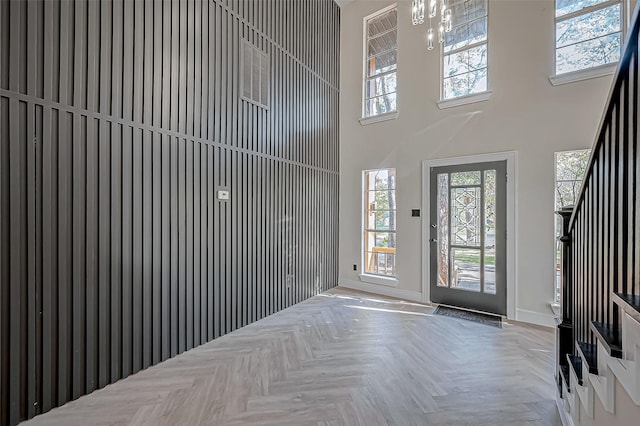 entryway featuring a wealth of natural light, a towering ceiling, and parquet flooring