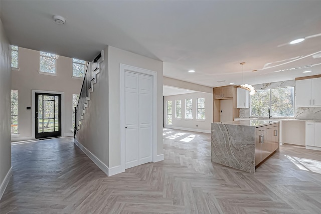 kitchen with white cabinets, decorative light fixtures, plenty of natural light, and light parquet flooring