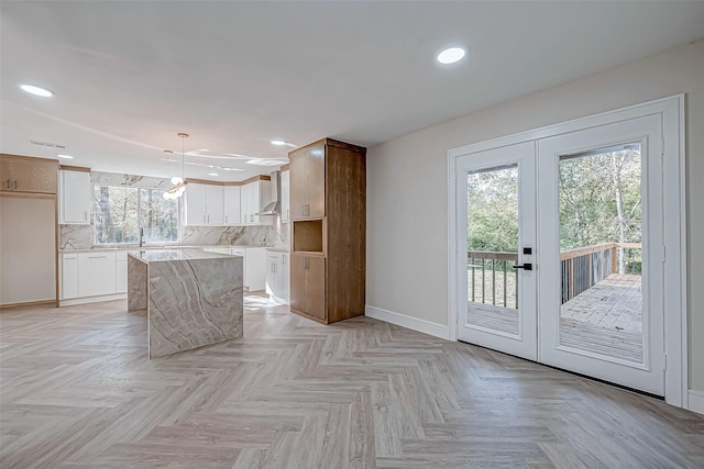 kitchen with white cabinets, a center island, decorative light fixtures, and a wealth of natural light