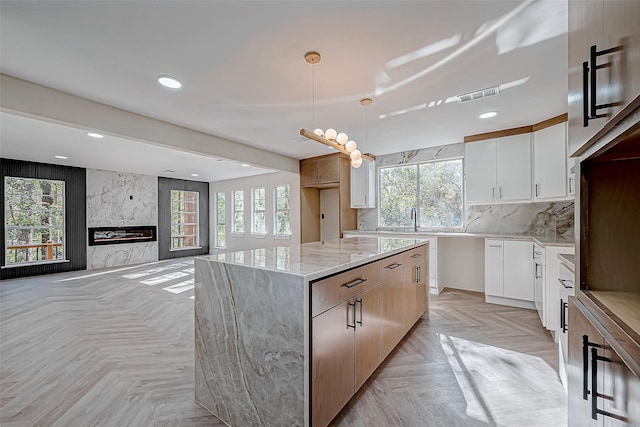 kitchen featuring white cabinets, a center island, a wealth of natural light, and light parquet flooring