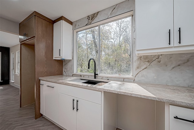 kitchen with light wood-type flooring, tasteful backsplash, white cabinetry, and sink