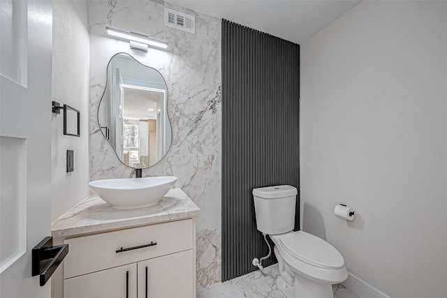 bathroom featuring vanity, toilet, and tile walls