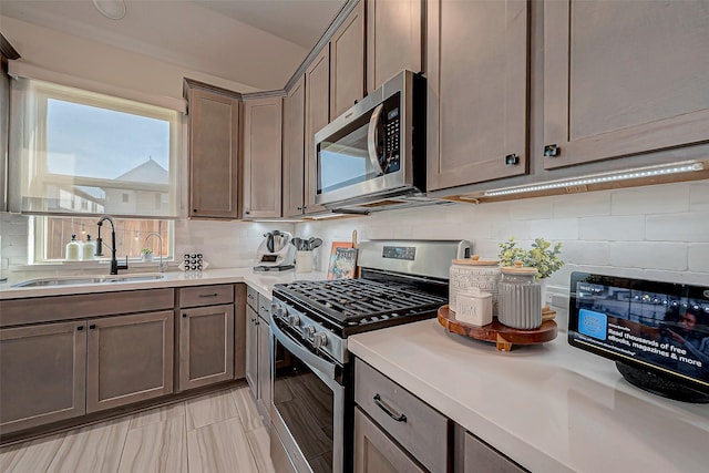 kitchen featuring backsplash, sink, and appliances with stainless steel finishes