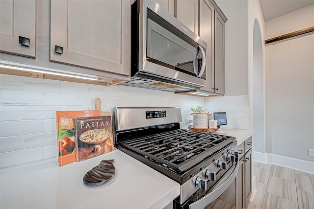 kitchen with decorative backsplash, stainless steel appliances, and gray cabinetry