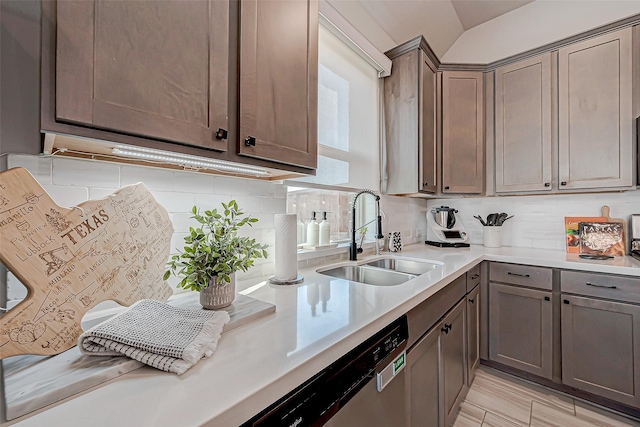 kitchen with dishwasher, sink, vaulted ceiling, decorative backsplash, and light wood-type flooring