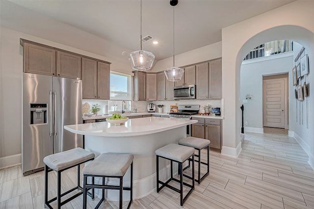 kitchen featuring appliances with stainless steel finishes, a kitchen island, pendant lighting, and a breakfast bar area