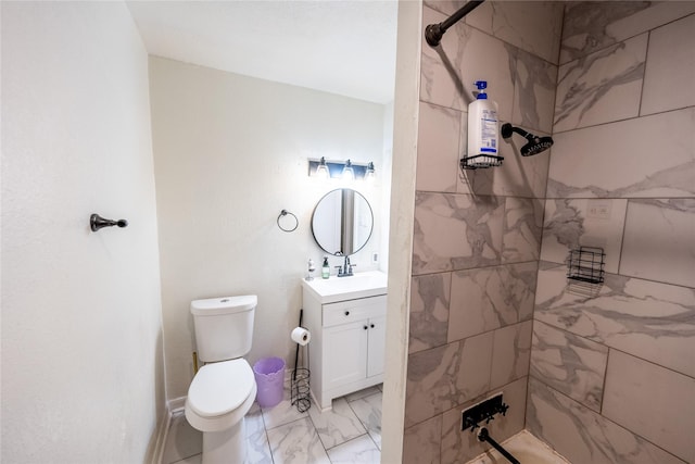 bathroom with tiled shower, vanity, and toilet