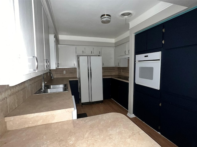 kitchen with decorative backsplash, white appliances, sink, dark hardwood / wood-style floors, and white cabinetry