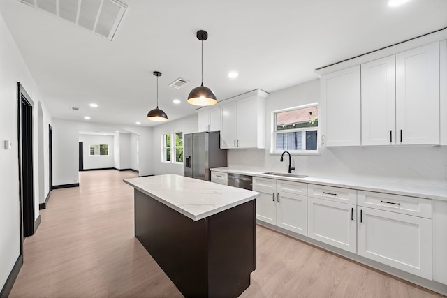 kitchen featuring appliances with stainless steel finishes, white cabinetry, a healthy amount of sunlight, and sink