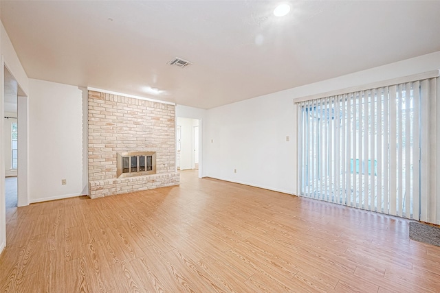 unfurnished living room with light hardwood / wood-style flooring and a brick fireplace