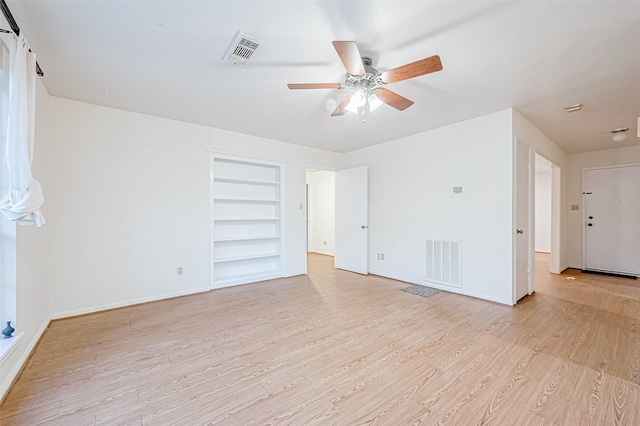 unfurnished room with built in shelves, light hardwood / wood-style floors, and ceiling fan