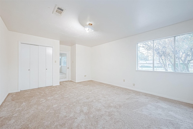 unfurnished bedroom with light carpet and a closet