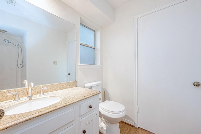 bathroom featuring a shower, vanity, hardwood / wood-style flooring, and toilet