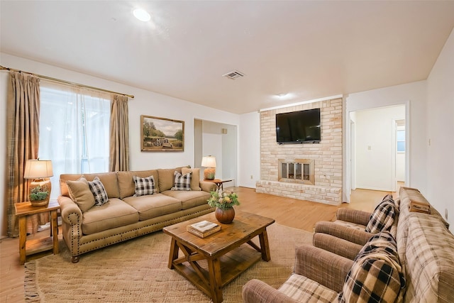 living room featuring light wood-type flooring and a brick fireplace