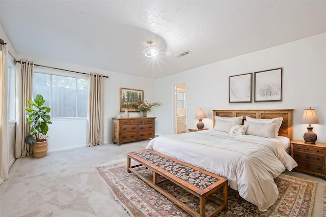 bedroom featuring light carpet and connected bathroom