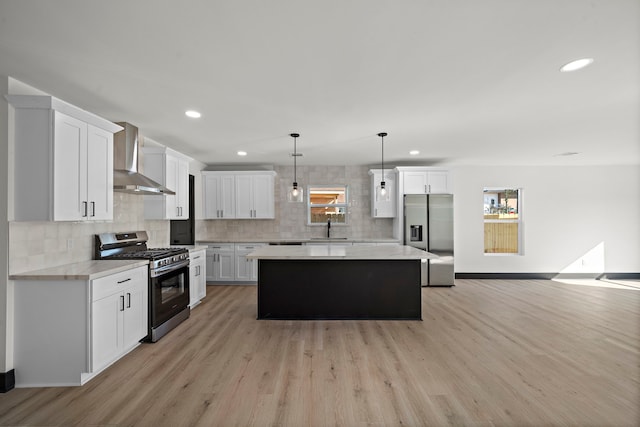 kitchen featuring a center island, wall chimney exhaust hood, stainless steel appliances, sink, and white cabinets