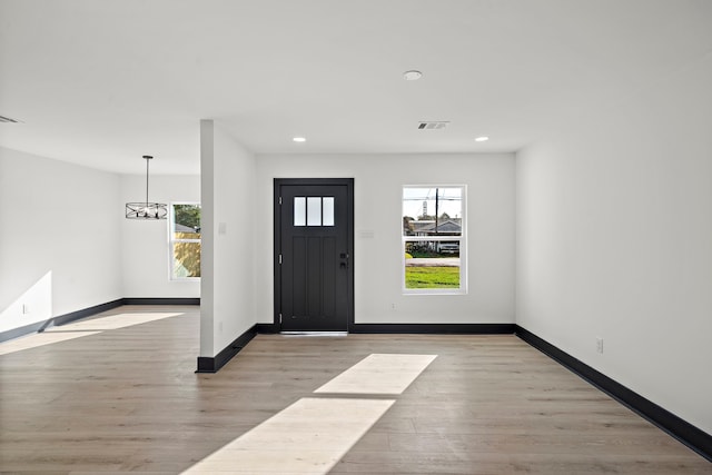 foyer with light hardwood / wood-style floors and a notable chandelier